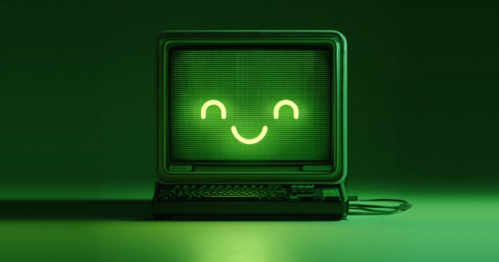 A green retro computer monitor with a smiling face glowing on its screen, eyes curved shut in a happy expression.